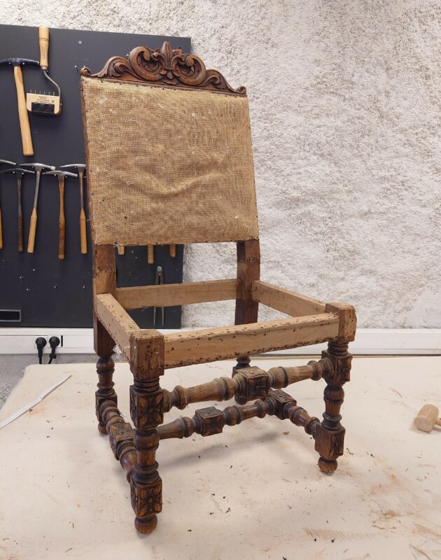 Detail of hand carved oak and fleur-de-lis motif on an antique Napoleon III chair frame