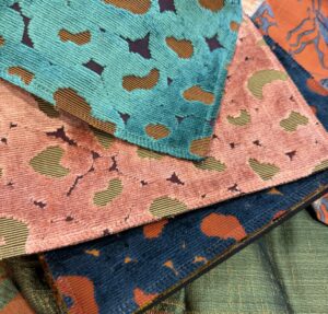 Samples of a Jim Thompson fancy velvet distributed by Pierre Frey, with abstract organic motifs where the flat woven ground shows through the pile, in turquoise, coral pink and navy blue