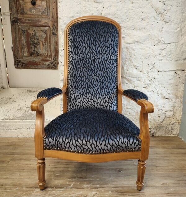 Voltaire armchair upholstered in navy blue viscose velvet, with a natural wood frame, in the upholstery workshop
